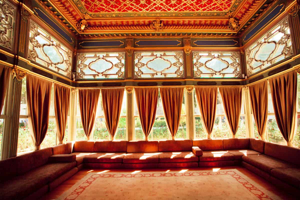 Red drapery and a wraparound divan leading toward Window salon at Topkapi Palace, Istanbul, Türkiye.